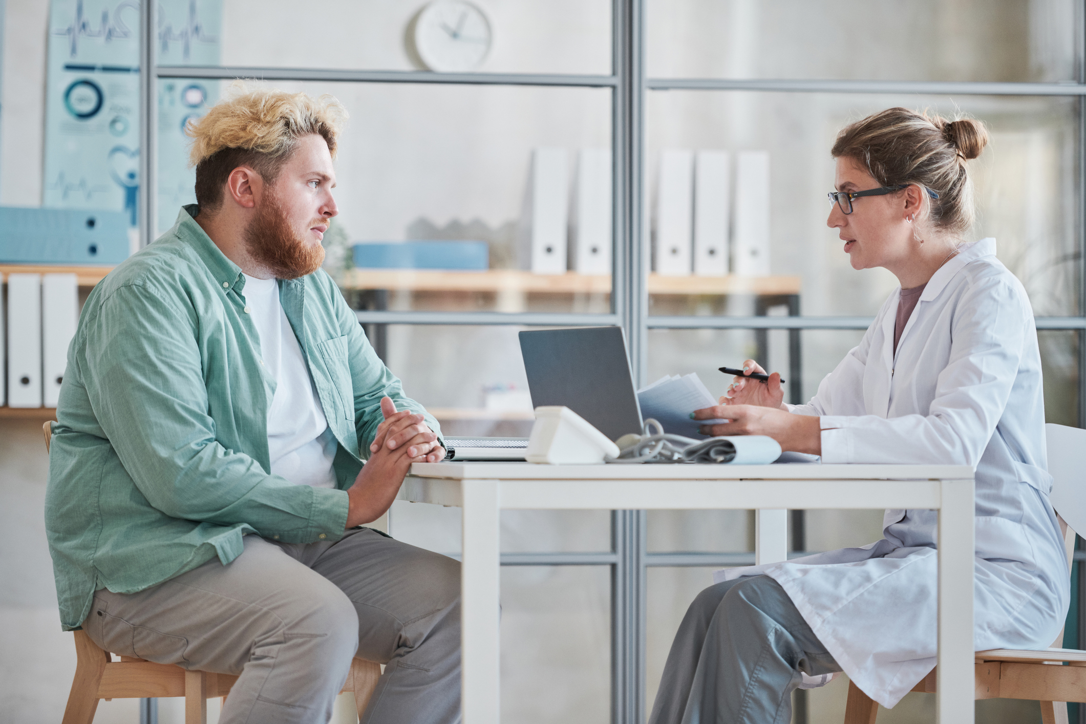 Eine Fachperson im Gesundheitswesen berät einen Patienten in einem Sprechzimmer zu Gewichtsmanagement und Gesundheit.