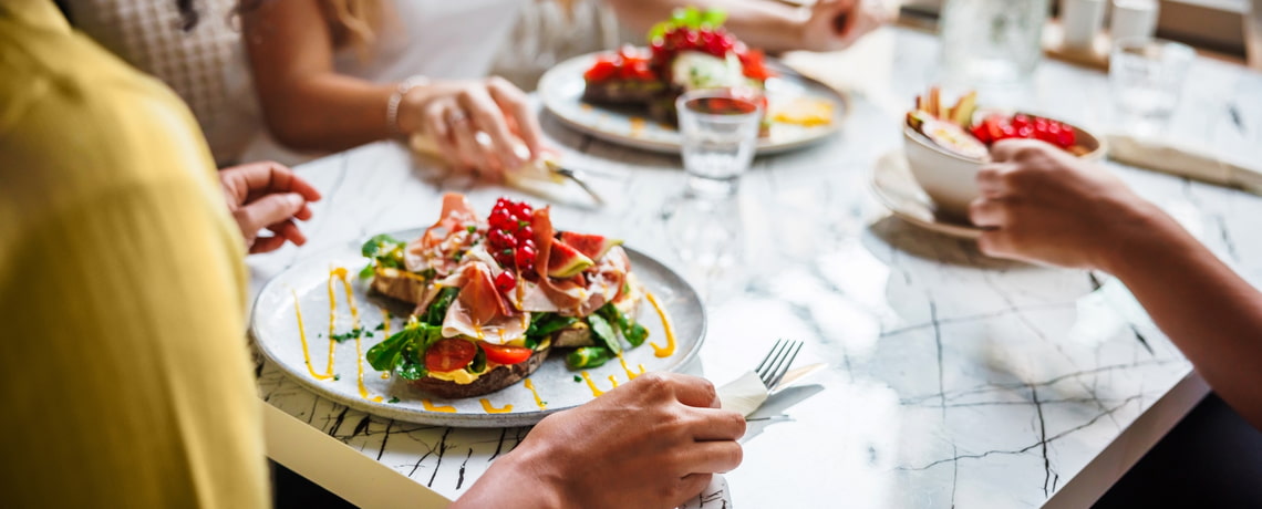 Drei Personen essen gemeinsam ausgewogene Mahlzeit.